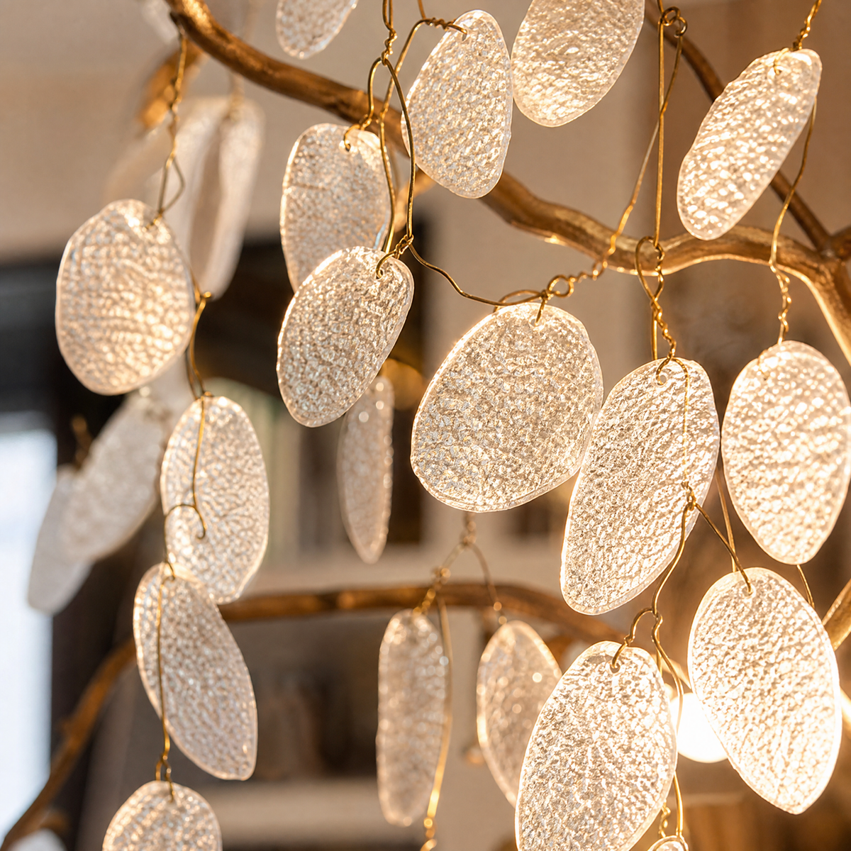 A modern organic branch chandelier with a warm gold metal frame and frosted white crystal petal accents.