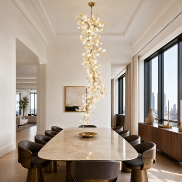 A tall gold cascading chandelier featuring metallic branches and crystal glass blossoms hanging in a high-ceiling space.